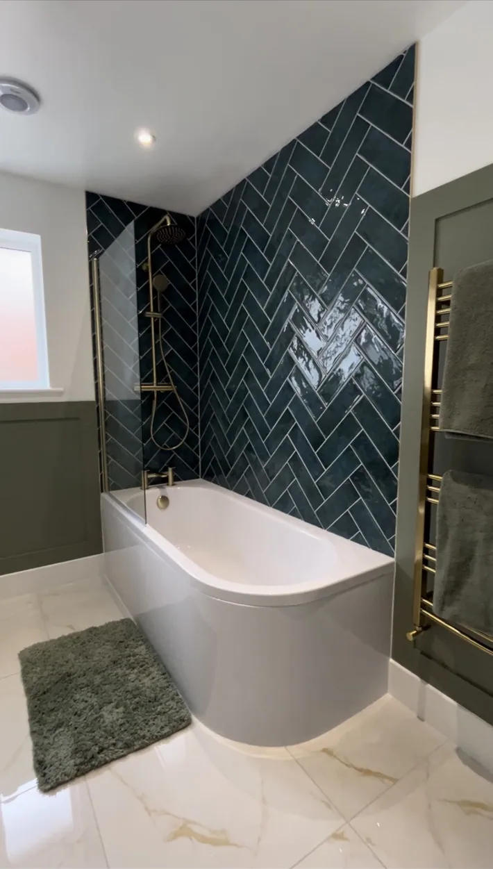 Completed bathroom with dark green herringbone tiles and freestanding bath